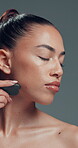 Gua sha, massage and skincare with woman in studio for cosmetics, dermatology or wellness routine. Aesthetic, beauty and facial treatment with model on gray background for circulation or drainage