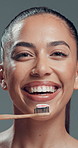 Brushing teeth, face and smile of woman in studio for oral care, hygiene or tooth whitening. Bamboo toothbrush, dental and toothpaste with happy model on gray background for cleaning or wellness