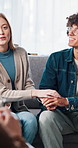 Talking, couple or holding hands in therapy on sofa for relationship advice, reconciliation or growth. Consultation, people and speaking to therapist in clinic for pre marriage counseling or guidance