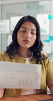 Creative, woman and reading document in office for performance, article sales and survey results. Person, laptop and review paperwork for copywriting, engagement graphs and infographic of publication
