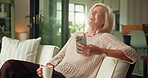 Phone, laughing and coffee with old woman on sofa for relax, social media meme and morning drink. Happiness, online funny video and drinking tea with senior person in living room of home for post