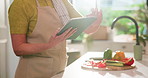 Hands, tablet and scroll in kitchen for cooking, vegetables and search for recipe online in home. Person, chef and flare for food with reading, ingredients or typing for meal prep on app in house