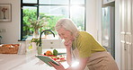 Cooking, tablet and mature woman in kitchen with online recipe for dinner, supper and cuisine. Happy, home and person on digital tech for video, food tutorial and culinary guide with ingredients