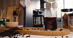 Glass, kitchen and pour milk in coffee for drink preparation, ice latte or morning brew. Caffeine, jar and beverage with dairy, liquid and cold refreshment in container with jug on table at home