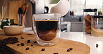Cup, home and pour milk in coffee with jug for drink preparation, espresso and morning brew. Caffeine, glass and dairy beverage for liquid refreshment, latte and cappuccino on table in kitchen