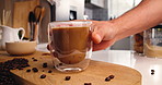 Cup, coffee and hands of person in kitchen of home for morning beverage, brewing or cappuccino liquid. Espresso shot, drink and latte with man in apartment for cafe mocha, roast and caffeine