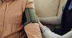 Hands, caregiver and blood pressure test on sofa with assessment for hypertension in retirement. Person, medical professional and monitor patient on couch, healthcare service and exam at nursing home