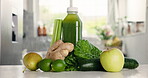 Green, ingredients and juice bottle on kitchen counter, detox and healthy drink for wellness benefits. Nutrition, gut health or container of liquid in home, raw fruits and organic vegetables for diet