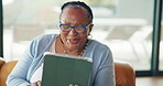 Video call, wave and elderly woman in house with tablet, hello or online conversation in living room. Digital, smile and senior person in retirement home with tech, kiss or connection on chat app.