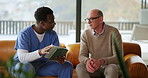 Talking, tablet and nurse with mature man in home for consulting, medical check up and help. Retirement, sofa and caregiver with person on tech for wellness, online diagnosis and healthcare support