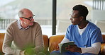 Consulting, tablet and nurse with mature man in home for medical service, check up and help. Retirement, sofa and caregiver with person on tech for wellness, online diagnosis and healthcare support
