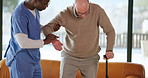 Man, nurse and helping elderly patient with walking stick for assisted living in retirement home. Male people, caregiver or aiding person with a disability for nursing, support or mobility in house