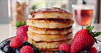 Maple syrup, breakfast and pancakes on table in kitchen for strawberry, nutrition and health drink. Fruit, food and dessert or brunch with honey on hotcakes in home for snack, cooking and herbal tea