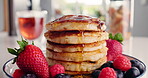 Maple syrup, pour and pancakes on table in kitchen for strawberry, nutrition and health drink. Fruit, food and dessert or brunch with honey on hotcakes in home for snack, breakfast and herbal tea