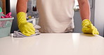 Gloves, cloth and wipe kitchen counter for dirt, germs and bacteria with basket for spring cleaning. Person, container and rag with ppe for dust, shine or chores with hands for hygiene at house