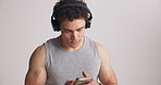Fitness, headphones and man in studio with phone for workout app, training and exercise routine. Sports, space and person on smartphone listening to audio, music and podcast on white background