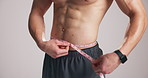 Hands, bodybuilder and tape measure for results in studio, waist and transformation on white background. Person, weight loss and check progress with muscle, abs and inspection for healthy body