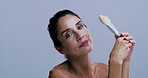 Face, woman and makeup brush in studio, glow and confident with tool, makeover and purple background. Mockup space, happiness and mature person with smile for foundation application or cosmetics