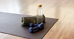 Yoga mat, dumbbells or bottle with towel in studio for fitness challenge, hydration or workout. Kneeling pad, weights or drink with cloth in gym for exercise, physical activity or liquid electrolytes