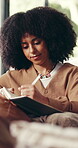 Writing, woman and creative with journal, home and ideas for fiction novel on couch and living room. Plan, story and African person with notebook for inspiration, info and author with notes in house