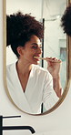 Woman, brushing teeth and mirror in bathroom with hygiene for cleaning mouth in morning. African person, toothbrush and reflection for oral care routine, dental wellness or plaque removal in house