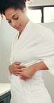 African woman, tie and gown in bathroom to start day, getting ready and spa preparation. Female person, adjust belt and bathrobe for self care, grooming routine and dressing for wellness at house