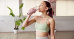 Fitness break, girl and drinking water in studio for hydration, pilates recovery and nutrition. Wellness, person or liquid bottle in health club for workout refresh, thirsty or rest from yoga routine