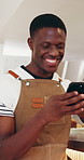 Phone, cafe barista and man typing, check schedule or sales information for stock. Mobile, coffee shop and happy black person reading online review for small business, text or update for inventory