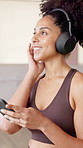 Happy woman, headphones and phone at gym with music, thinking and listen with streaming at fitness club. Person, smile and smartphone with mobile app, subscription and reflection at wellness class