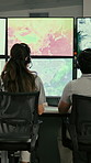 Woman, headset and screen with maps in control room to monitor weather, climate change and satellite. Back, people and point to pc with hurricane surveillance, study storm pattern and global cyclone