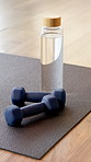 Water, empty and dumbbells in yoga studio on floor for workout routine, exercise and fitness class. Background, health club and equipment, bottle and weights on mat for wellness, pilates and gym
