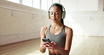 Headphones, smartphone and woman in studio, fitness and texting with social media. Sound, exercise and person in health club, cellphone and music break with album playlist, app and message to contact