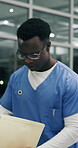 Night, black man and doctor with paperwork in hospital, medical info or emergency patient preparation. Urgent care, late shift or physician reading health chart, ambulance arrival and plan for crisis