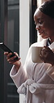 Black woman, phone and coffee in bedroom with window, smile and texting for contact or notification in home. African person, smartphone and happy with warm drink, web chat and social network at house