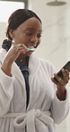 Black woman, phone and brushing teeth in bathroom with mobile app, networking and dental hygiene. Oral care, tech and female person cleaning mouth for morning routine with social media and texting