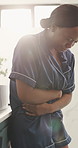 Black woman, stomach ache and cramps in home with menstruation, stress or ulcer with belly in morning. African person, pain and period with pcos, constipation and frustrated with indigestion at house