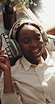 Black woman, headphones and relax on sofa with smile for music, listening with streaming in home living room. Person, above and dance for subscription, audio and relief on couch with peace in house