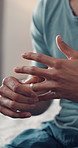Hands, person and fidget with wedding ring on bed for divorce, separation and marriage problems. Closeup, man and doubt with jewellery for toxic relationship, commitment issues and decision at house