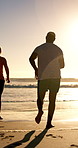 Senior couple, running and happy at beach, sunset or outdoor for bonding, fitness and space in sky. Elderly man, woman and interracial relationship for exercise, excited or playful by ocean in summer