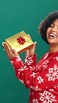 Gift box, christmas and face of woman in studio for festive celebration, holiday or event. Happy, giveaway and portrait of excited female person with xmas present for tradition by green background.