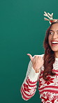 Christmas, announcement and pointing with woman in studio for deal, promotion or sale. Giveaway, space and celebration with happy person on green background for festive season or retail marketing