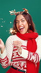 Christmas, face and happy woman with sparklers in studio, dancing and heart sign for celebration. Portrait, hand firework and dancer excited for holiday season on green background, festive or gesture