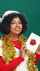 Woman, face and Christmas present in studio, shake or santa hat for festive holiday on green background. Girl, excited and guess with gift box, portrait and happy for xmas celebration in Costa Rica