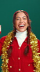 Christmas, dance and face of happy woman in studio for holiday, vacation and festive season. Excited, decoration and portrait of person with energy for party, xmas and celebration on green background