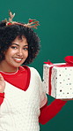 Happy woman, face and christmas with gift box for festive celebration on a green studio background. Portrait, female person or model with smile or shopping bag for december, presents or holiday
