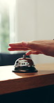 Person, hands and ring with bell for service, customer help or assistance on counter in hotel. Closeup, concierge or welcome guest asking for hospitality, accommodation or check in station at lodge