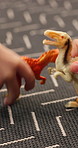 Children, hands or play in home with dinosaur for entertainment, imagination or bonding together. Friends, animal toys or plastic reptile fight on carpet for fun activity, fantasy game or creativity.