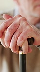 Balance, hands and walking stick with senior man in retirement home for recovery or rehabilitation. Cane, support and wellness with old person closeup in apartment for arthritis or parkinsons