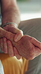 Wrist pain, cramp and hands of man in home for fibromyalgia, emergency and pressure crisis. Joint inflammation, osteoarthritis and sprain with senior person in living room of apartment for injury