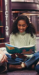 Girl, student or reading with book in library for story, knowledge or literature learning in school. Child, kid or learner with tutor, novel or lesson for education or childhood development in study
